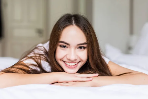 Mujer encantadora sonrisa cara de cerca y ella acostada en la cama por la mañana —  Fotos de Stock