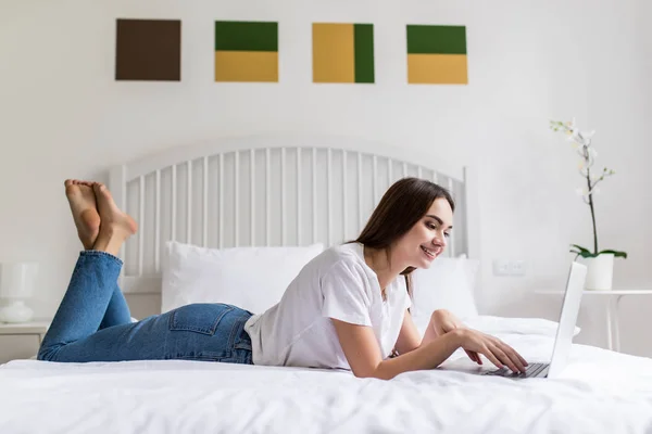 Piękna młoda kobieta relaks na łóżku w pracy z jej laptop — Zdjęcie stockowe
