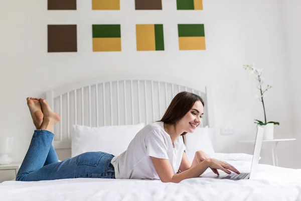 Happy casual piękna kobieta pracuje na laptopie siedzi na łóżku w domu. — Zdjęcie stockowe