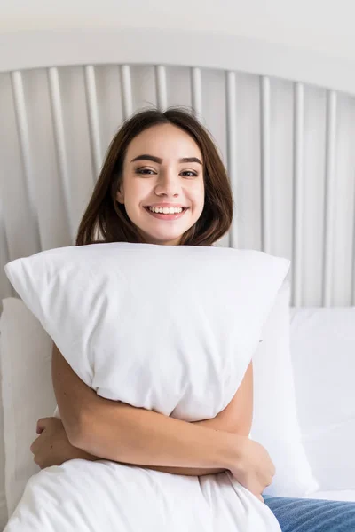 Zmysłowy uśmiechający się młoda kobieta siedzi na łóżku i tulenie biały — Zdjęcie stockowe