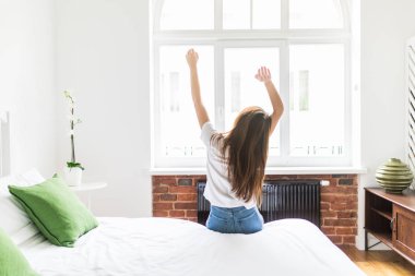 Mutlu genç kadın sabah yatağında uyanır..