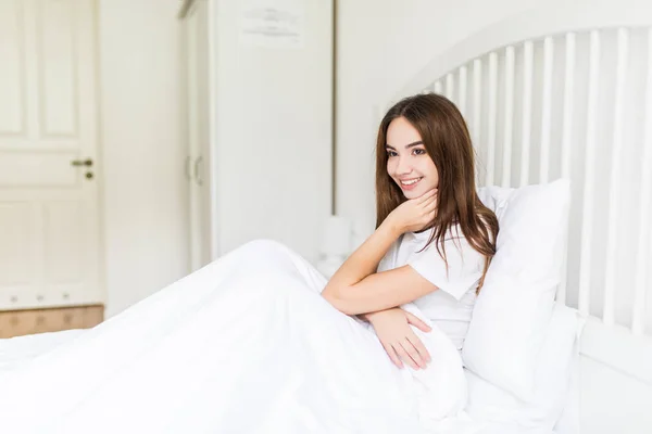 Porträt hübsches junges Mädchen auf Bett unter Bank in moderner Wohnung am Morgen. — Stockfoto