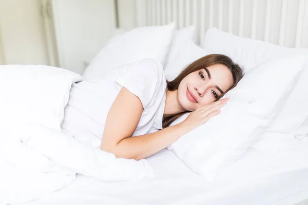 Femme dormant dans son lit. Belle jeune femme souriante dormant au lit — Photo