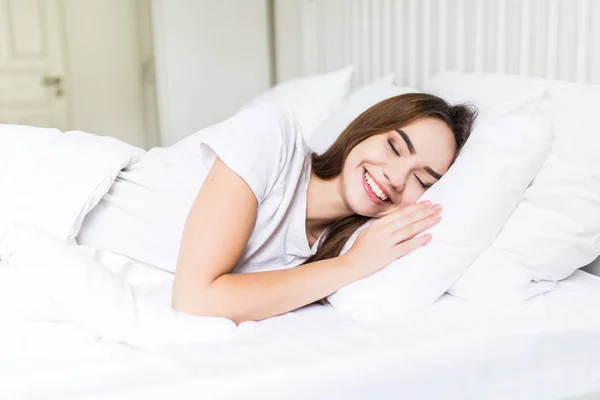 C'est l'heure de se détendre. Jeune femme souriante couchée sur le lit et gardant les yeux fermés — Photo