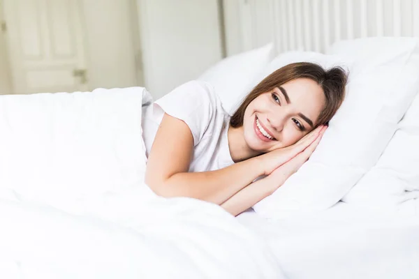 Brune décontractée souriante couchée dans son lit dans une chambre lumineuse avant de dormir — Photo