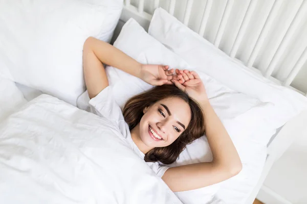 Image de jeune femme heureuse habillée se trouve sur le lit à la maison à l'intérieur . — Photo