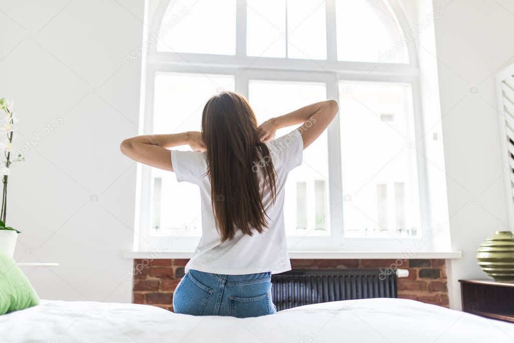 Happy morning. Attractive young woman stretching near window at her apartment.