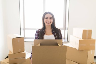 Young woman is transporting a filled cardboard in new apparment clipart
