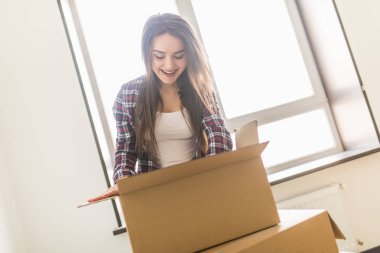 Woman packing and unpacking in a carton box when moving home clipart