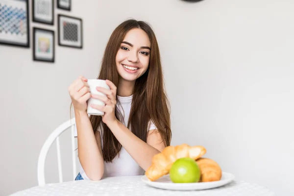 Retrato de una hermosa joven desayunando en la cocina por la mañana — Foto de Stock
