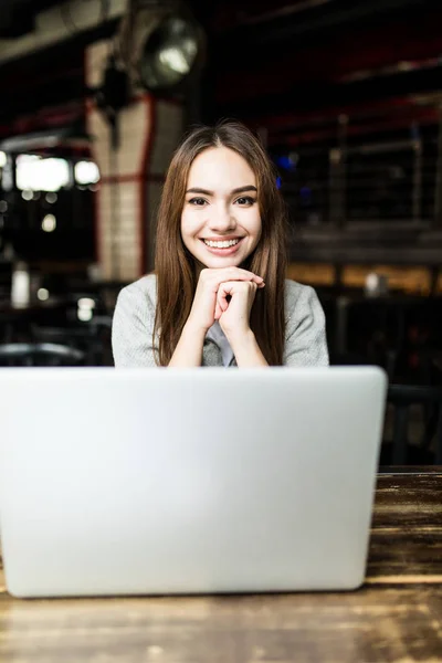 Mujer joven e independiente sentada en la cafetería use laptop y beba café — Foto de Stock