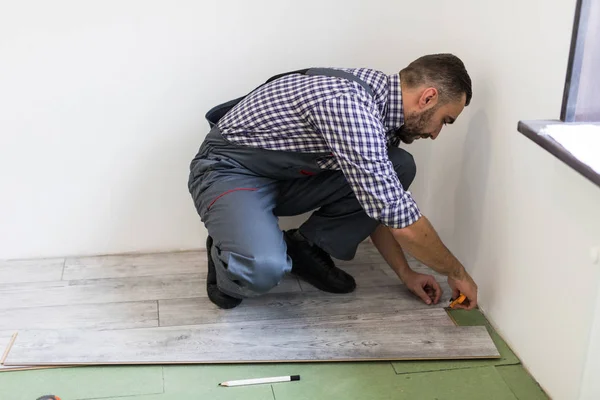 Man worker installing new wooden laminate flooring in new apparment — Stock Photo, Image