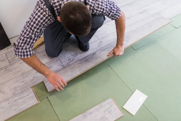 Чоловік встановлює нові дерев'яні ламінатні підлоги в новому обладнанні — стокове фото