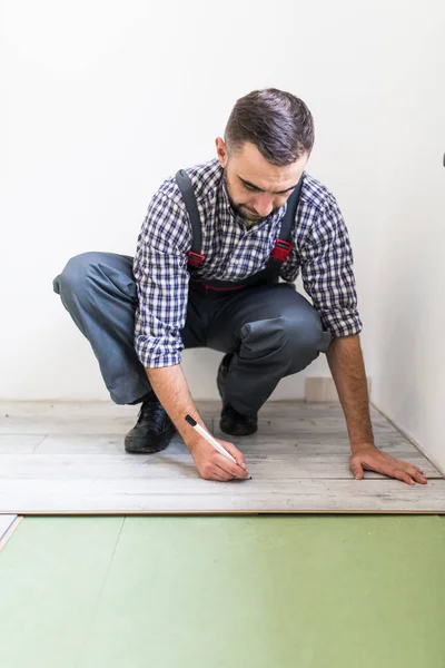 Male worker installing laminate flooring, man installing new wooden laminate flooring. Man laying laminate flooring at home. Carpenter worker installing laminate flooring in the room — Stock Photo, Image