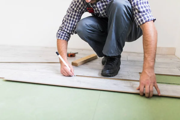 Primer plano hombre manos trabajador instalación de pisos laminados en la nueva habitación — Foto de Stock