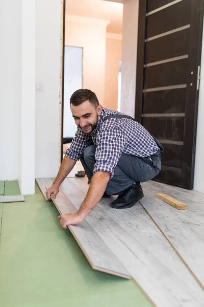 Worker man is repairing the floor in the house, laminate flooring in the style of old boards — Stock Photo, Image