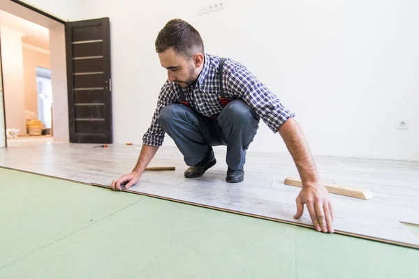 Carpenter worker man installing wood parquet board during flooring work with hammer — Stock Photo, Image