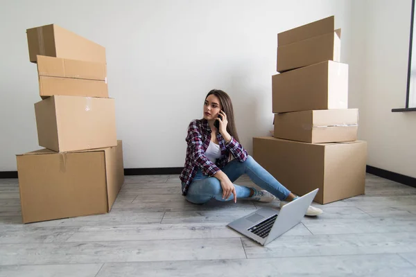Ung kvinna flyttar in i ett nytt hus som sitter ner på golvet i tom lägenhet och beräkna hem budget. — Stockfoto