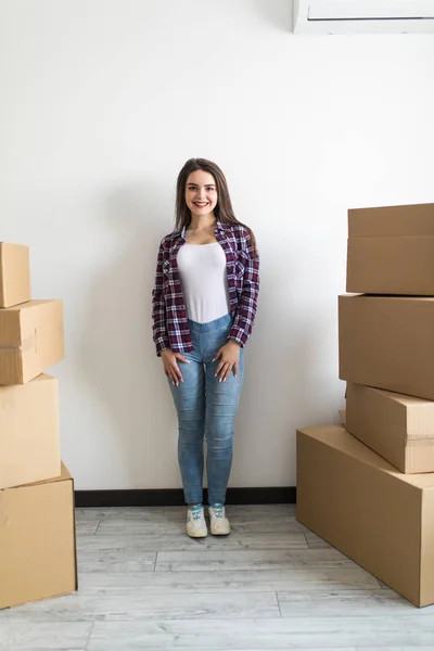 Attraktiv ung kvinna är på väg, stående bland kartonger, leende — Stockfoto