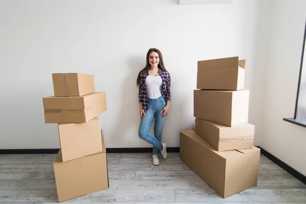 Jeune femme séduisante est en mouvement, debout parmi les boîtes en carton — Photo