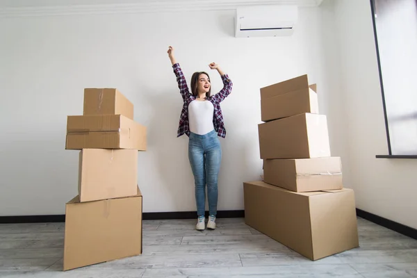 Glad ung kvinna står i nya lägenheten med arm upp efter flytten i nya lägenheten — Stockfoto