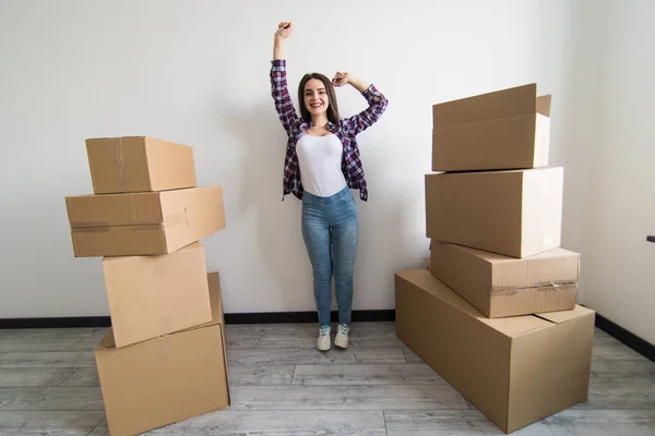 Glad ung kvinna står i nya lägenheten med arm upp efter flytten i nya lägenheten — Stockfoto