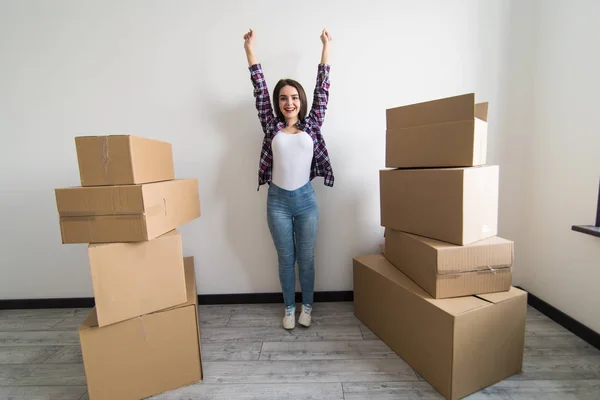 Ung glad kvinna, student, flyttade in i en ny lägenhet. Packar lådor i det nya huset och höjde händerna upp som ett tecken på framgång. — Stockfoto