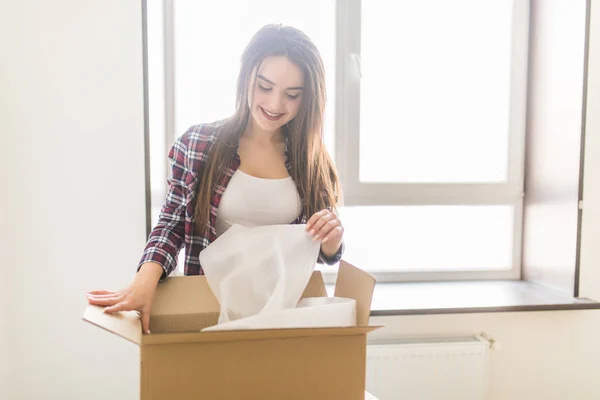 Szczęśliwa młoda kobieta rozpakowaniu pudełka w nowym domu. Koncepcja ta ruchoma — Zdjęcie stockowe