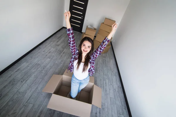 若い興奮して新しい家に移動した後上げられた手の cardbox 中座っている女性 — ストック写真