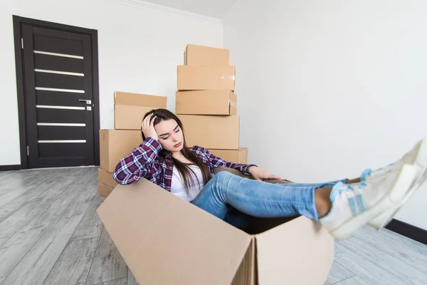 Glada ledsen och trött kvinna som sitter i en kartong vit flyttar i nya appartmant — Stockfoto