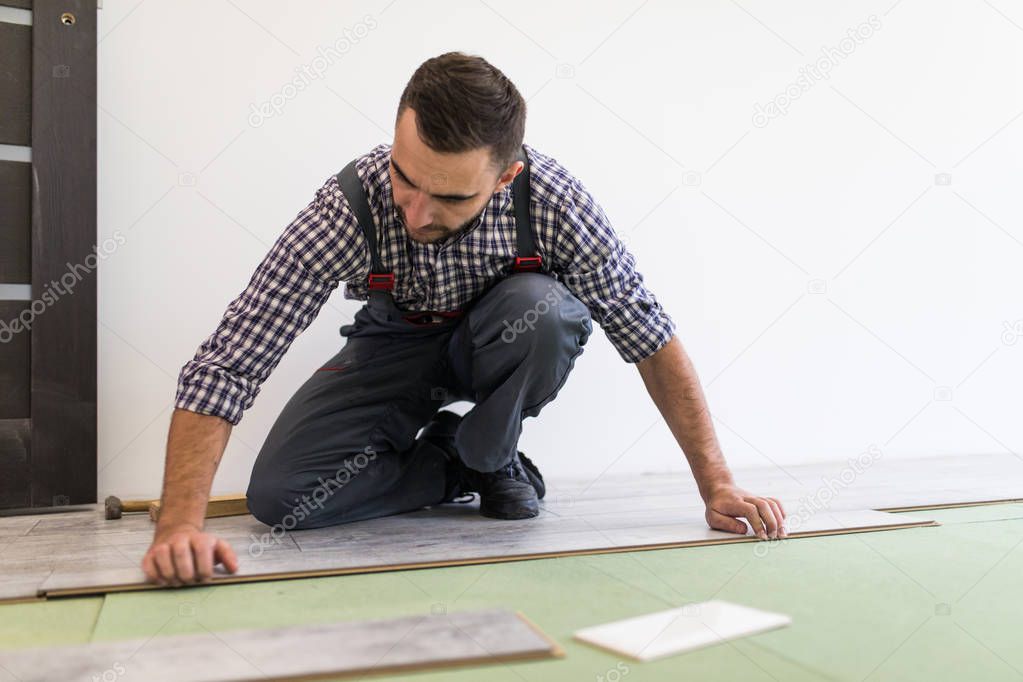 Carpenter worker installing laminate flooring in the new room