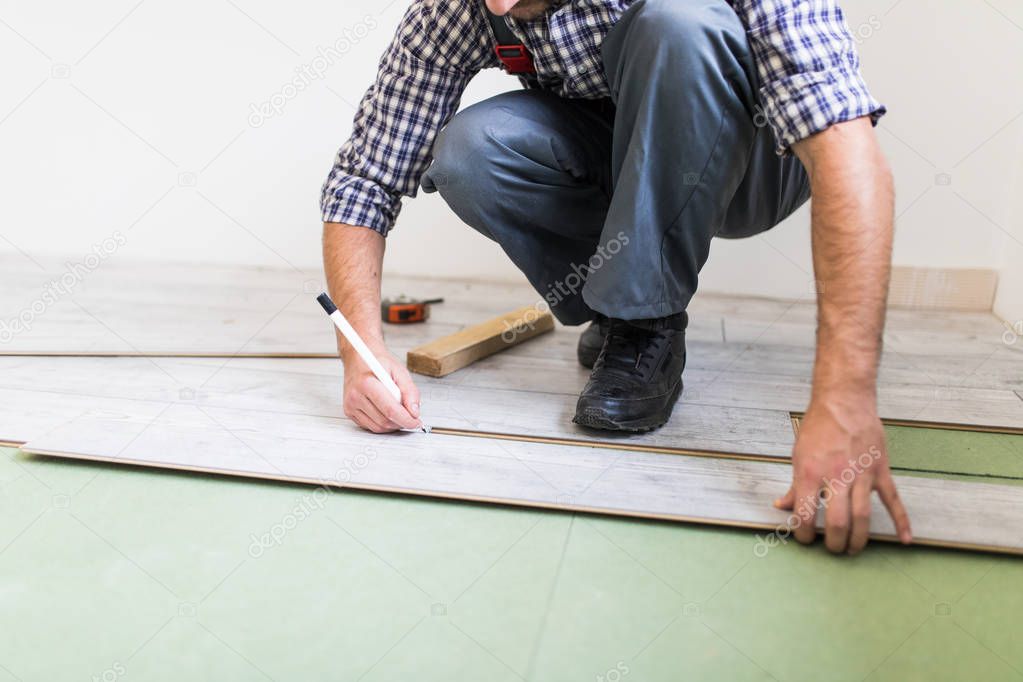 Close up man hands worker installing laminate flooring in the new room