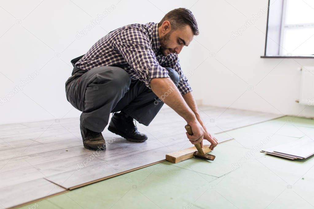 Worker Man laying laminate flooring in construction concept