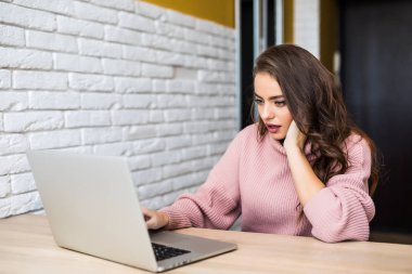 Laptop arıyorum ve Oda evde masada oturan şok ifade güzel genç kadın