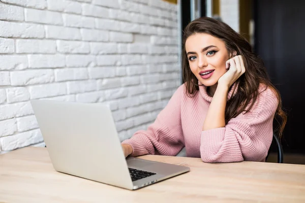 Happy casual beautiful woman working on a laptop sitting at table in the house. — Stock Photo, Image