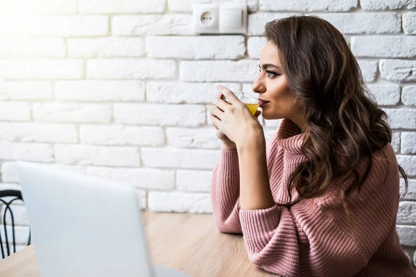 kahve fincanı ve dizüstü evde mutfakta gülümseyen genç kadın