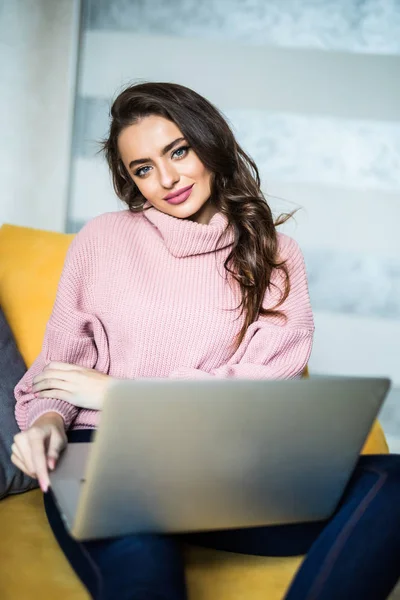 Young beautiful woman using laptop computer smiling happy watching and browsing or doing online internet shopping at home modern living room in cheerful and satisfied face expression — Stock Photo, Image