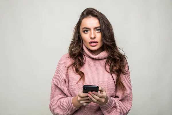 Portrait of pretty glad girl typing sms to her friend over white background — Stock Photo, Image