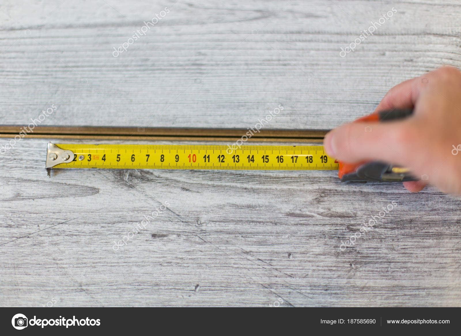 Workers Installing Wooden Laminate Flooring And Measuring Workers Installing Wooden Laminate Flooring And Measuring Board Before Cutting Stock Photo