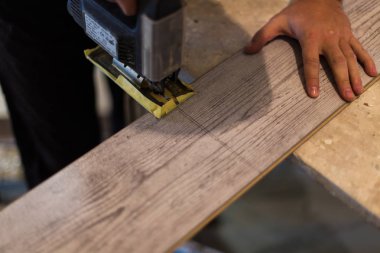 Yüklenici kesme laminat döşeme boyuna. Kesme işçi döşeme elektrikli testere ile laminat..