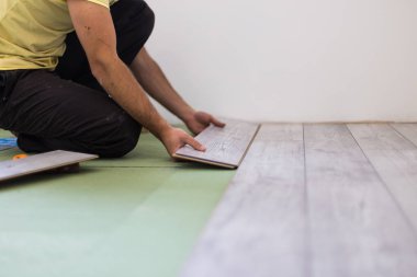 bir ev tadilatı sırasında laminat panoları koyan el ulağı. Eller yukarı