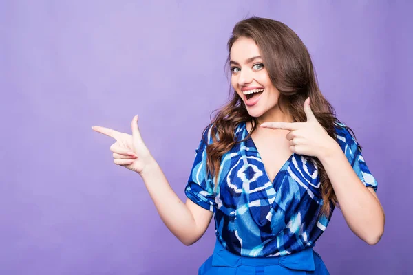Usmívající se žena ukazující prst straně na fialovém pozadí — Stock fotografie