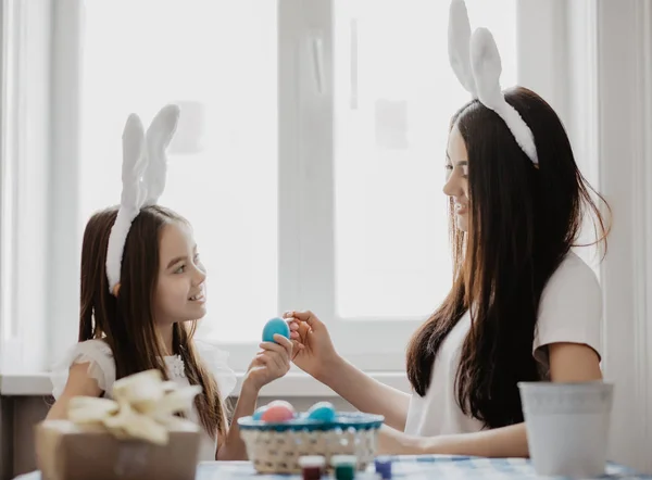 easter, family, holiday and child concept. Little girl and mother coloring eggs for easter
