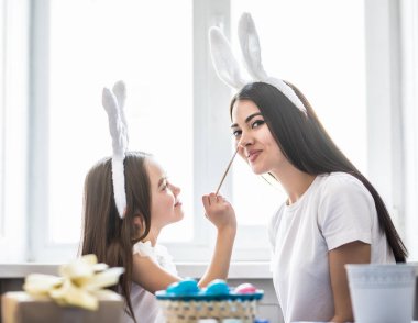 Sevgi dolu anne ve kızı boyama Paskalya yumurta ve beyaz birbirimizi iyi eğlenceler. Rahat ev atmosfer. Paskalya