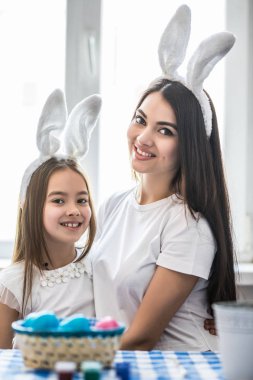 Yakışıklı, çekici, güzel, tatlı anne ve kızı sarılma, Paskalya için hazırlanıyor kameraya, seyir gülümseyen harcama, birlikte vaktinizi, tavşan kulakları giyiyor.