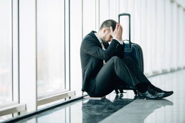 Bir şey, endişe ciddi iş adamı oturan ve Havaalanı terminal başına dokun. İş adamı uçağını özledim. Duygu hasta iş gezisi önce genç adam.