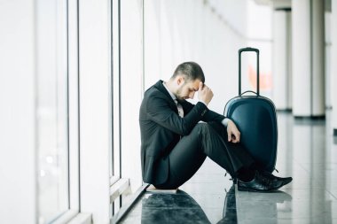Bavul uçuş gecikme, baş, baş ağrısı, seyahat bekleyen iki elle dokunarak ile katta terminal Havaalanı'nda oturan iş adam. İş gezisi