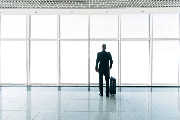 Immagine sagomata vista posteriore di uomo d'affari con bagagli guardando attraverso la finestra in aeroporto — Foto Stock