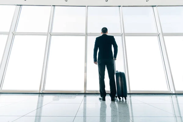 Geschäftsmann am Flughafen mit Koffer, der am Gate auf Abflug wartet. Geschäftsreisen — Stockfoto