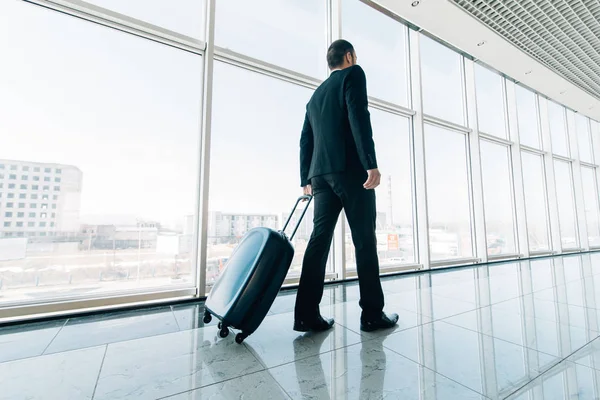 Człowiek na lotnisku z walizką chodzenie do bramy. Podróż służbowa. — Zdjęcie stockowe